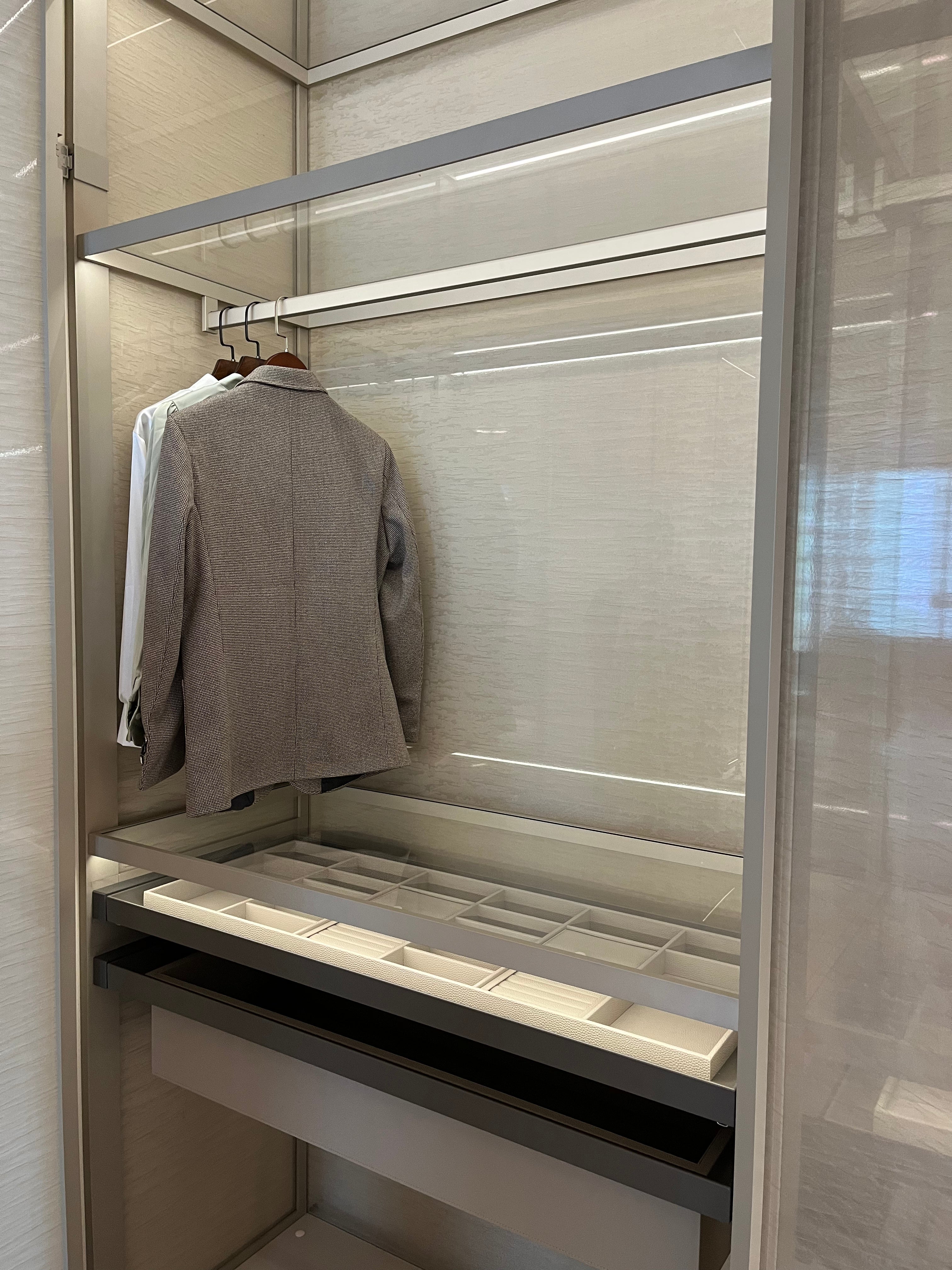 Illuminated glass wardrobe interior with hanging rail and accessory storage